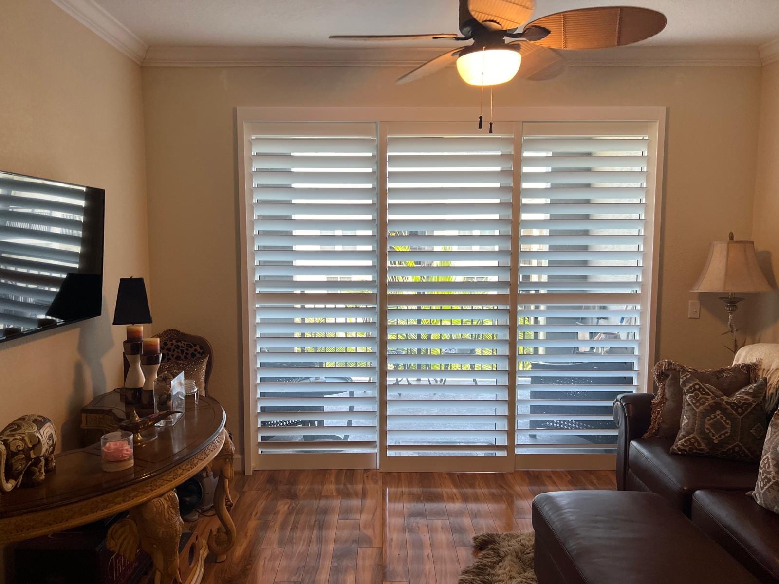White shutters across a wide sliding door behind a leather sofa