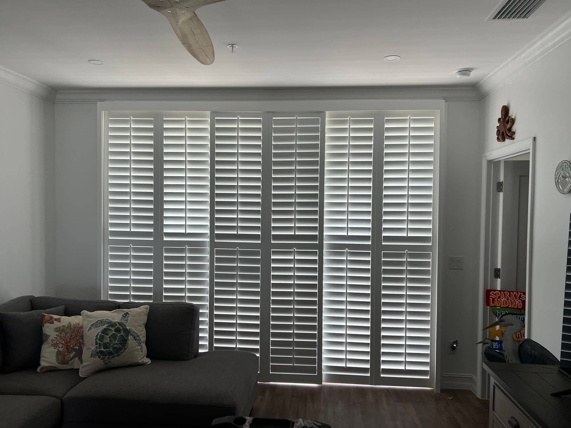 White bypass shutter panels covering a full-width sliding glass door