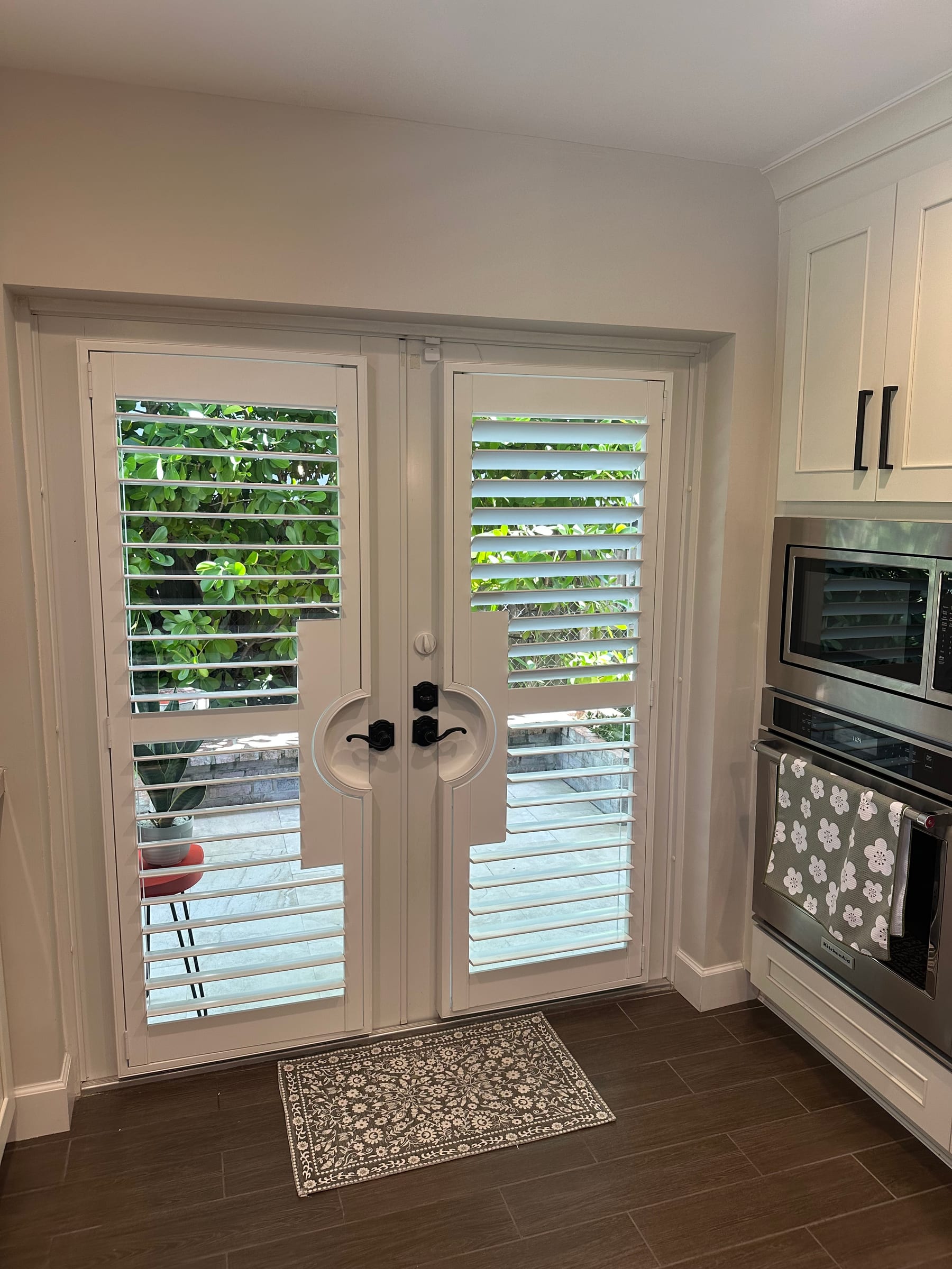 White shutters on a pair of glazed garden doors beside a kitchen wall oven