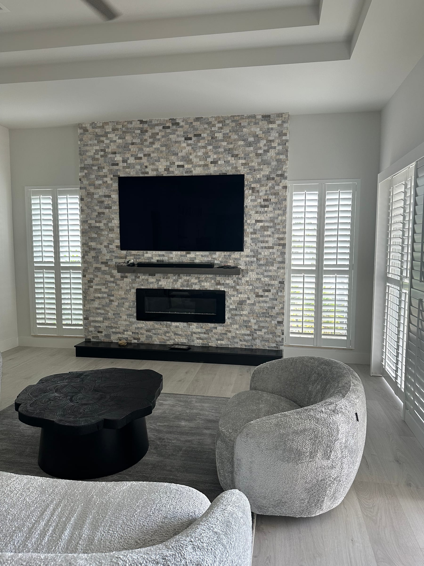 White shutters on windows either side of a stone fireplace wall