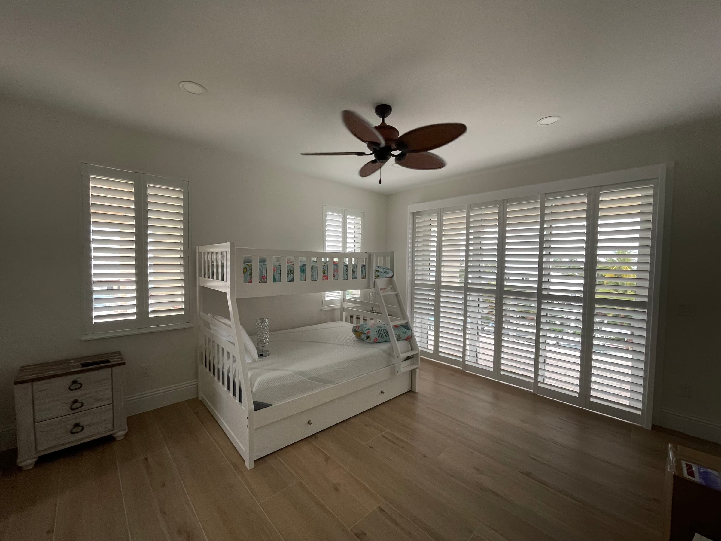 White shutters on bedroom windows beside a wooden bunk bed